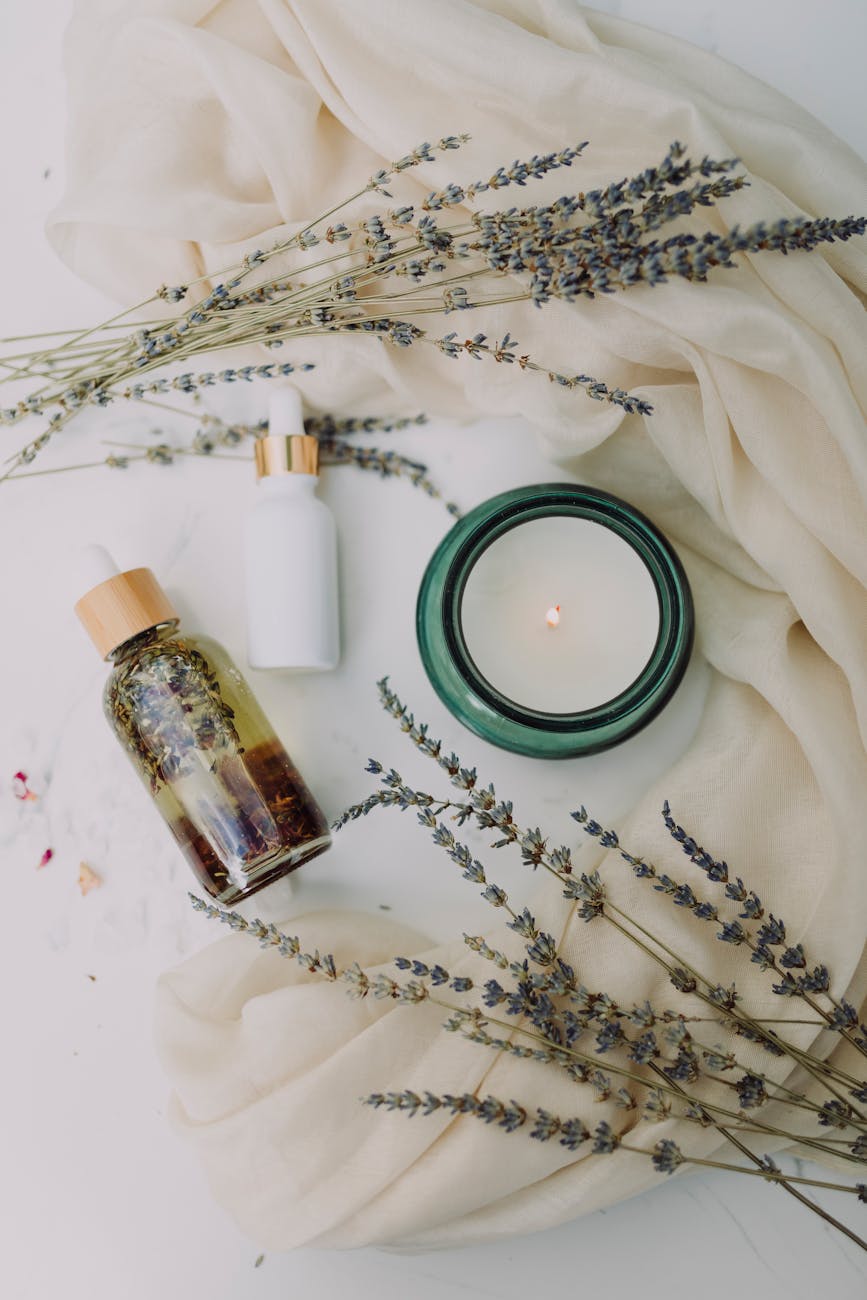 Dried flowers, a candle, and tinctures lie on the white folds of a sheet